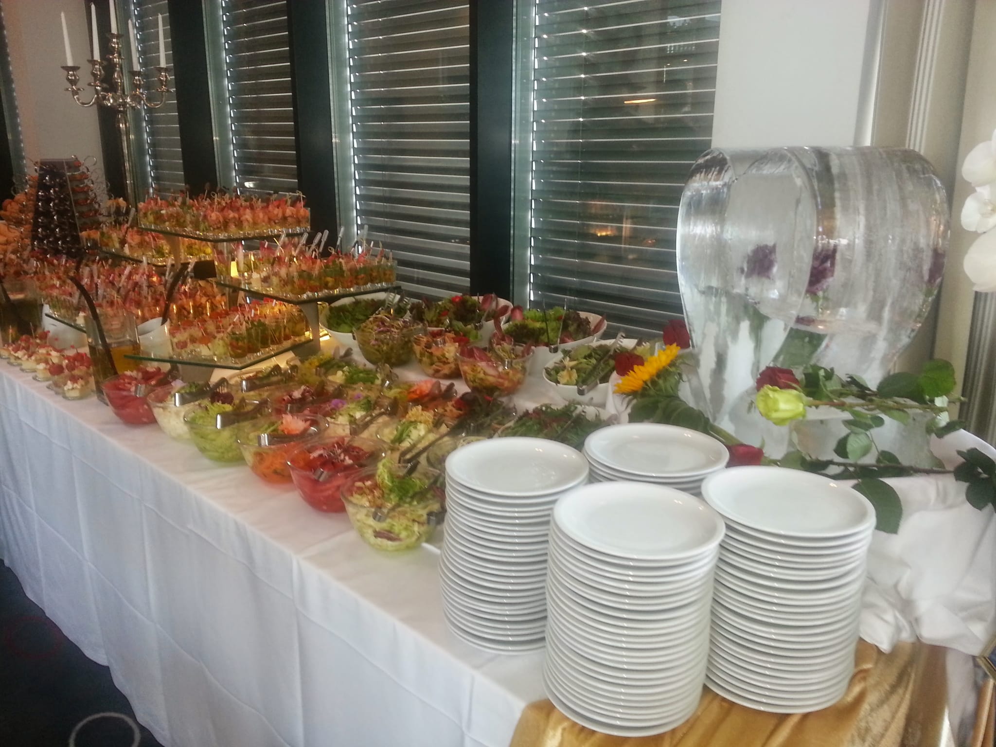 Buffet mit Fingerfood-Etageren, Salaten und Tellerstapeln
