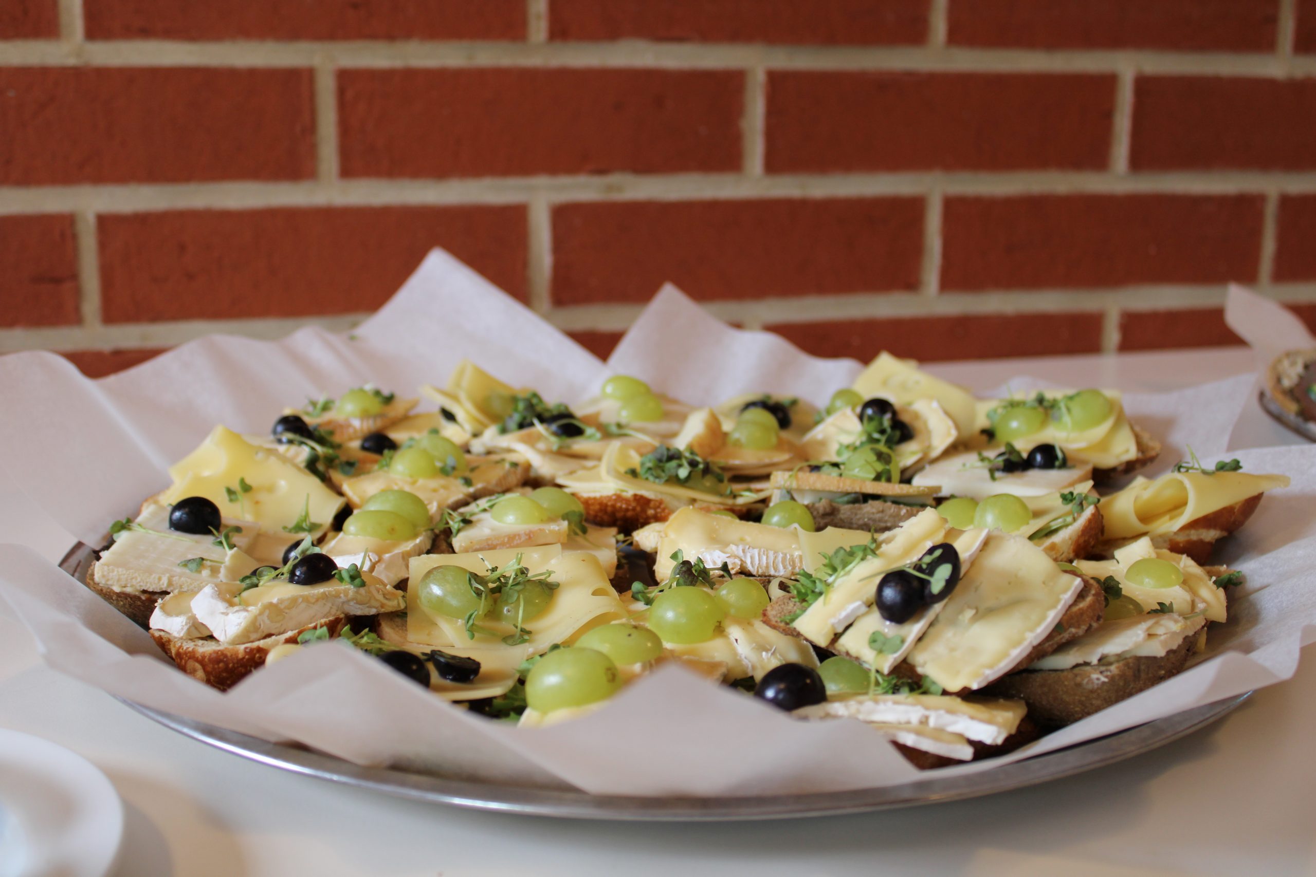 Platte mit Käse-Canapés, Trauben und Oliven