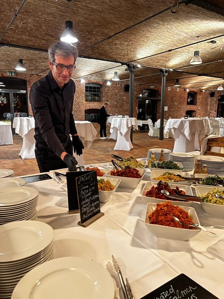 Servicekraft von HAM-Event richtet ein Salatbuffet in einem Gewölbekeller an