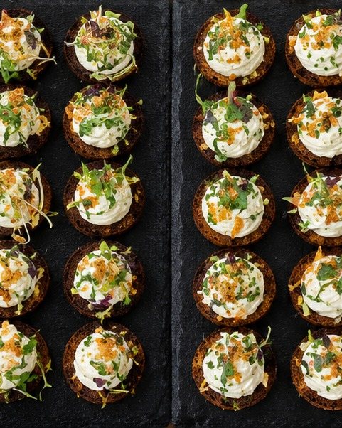 Fingerfood auf Schwarzbrot mit Frischkäse und Kresse auf Schieferplatten
